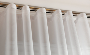 Close-up of white sheer curtains hanging from a curtain rod.