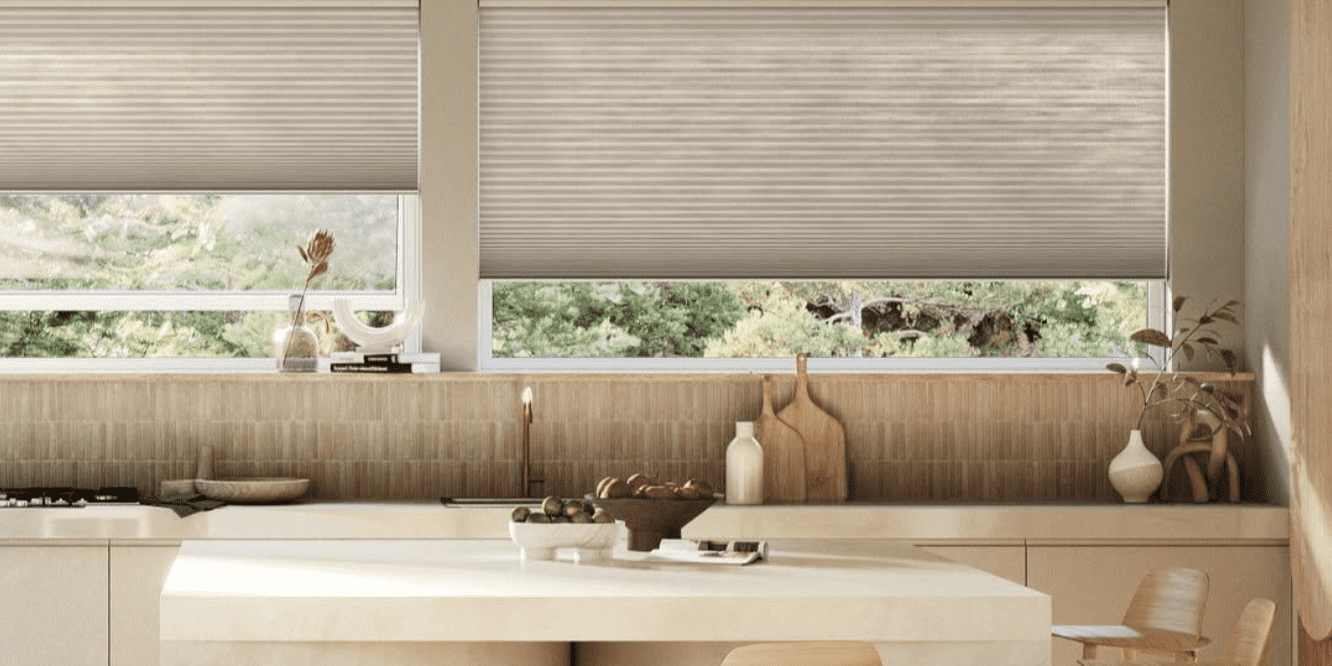 motorized-cellular-shades-specialty-shaped-windows-denver.jpg Modern kitchen with light wood cabinets, a curved island with two wooden stools, and large windows with beige blinds letting in natural light.